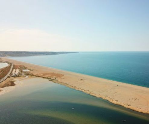 Aerial view of a stretch of Chesil Beach looking out towards the sea and Portland