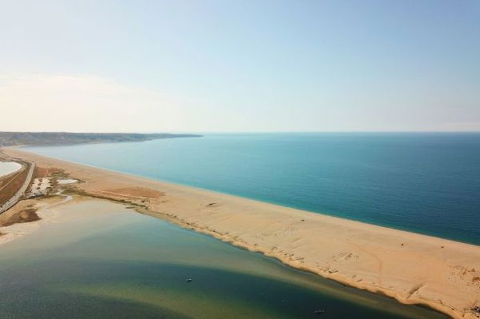 Aerial view of a stretch of Chesil Beach looking out towards the sea and Portland