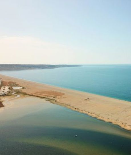 Aerial view of a stretch of Chesil Beach looking out towards the sea and Portland