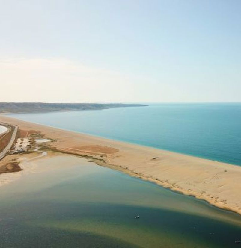 Aerial view of a stretch of Chesil Beach looking out towards the sea and Portland