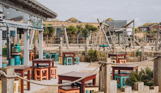 An outdoor beach bar and street food shack with outdoor seating and a children's play area by the sea