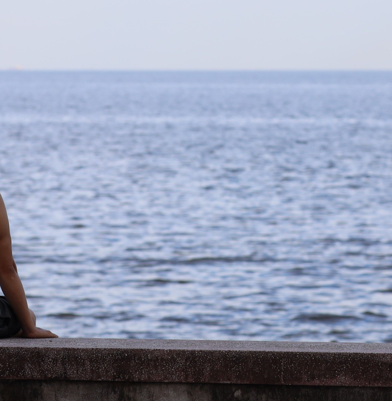 A man sat on a wall doing nothing looking out to sea
