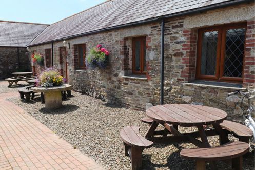 External of a cottage courtyard area with outdoor benches and flowers