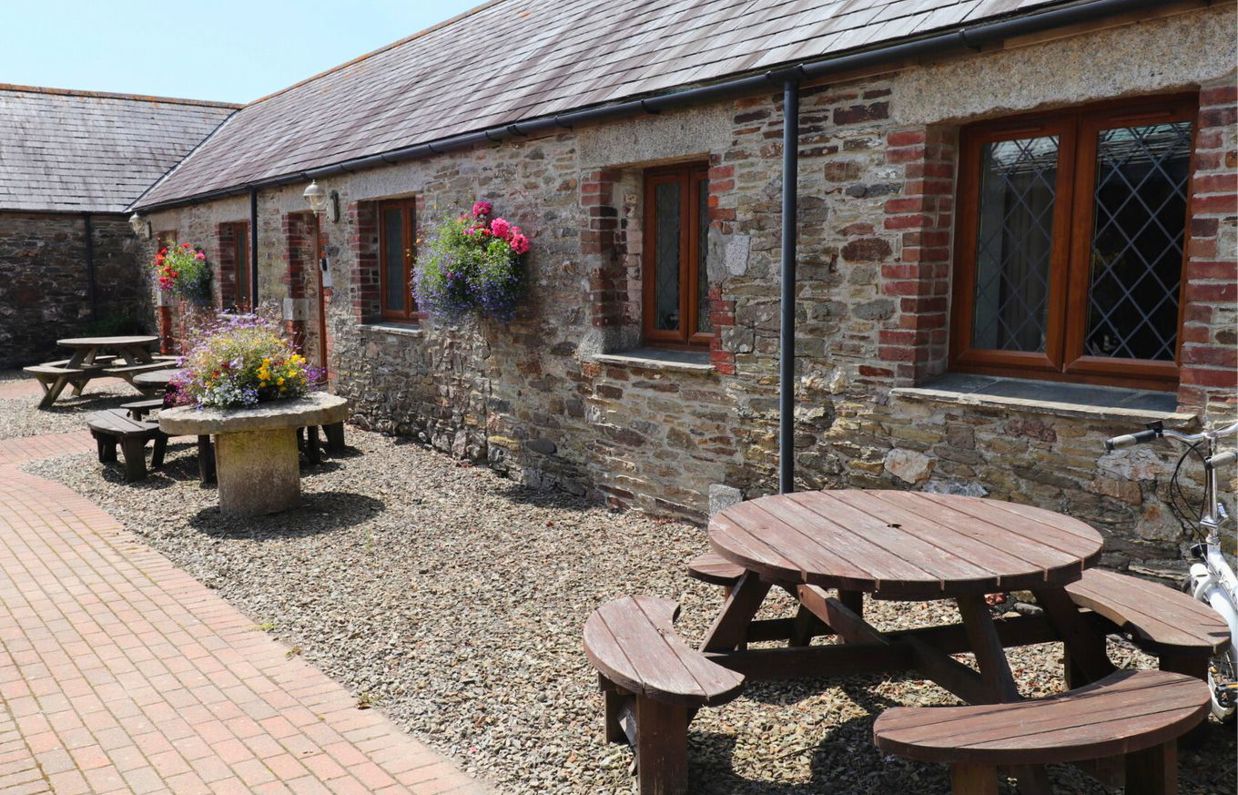 External of a cottage courtyard area with outdoor benches and flowers