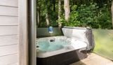 External of a lodge on pitch with hot tub among woodland