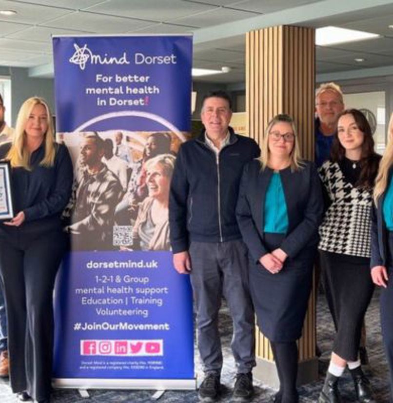 A group of people stood together smiling at the camera with Dorset Mind