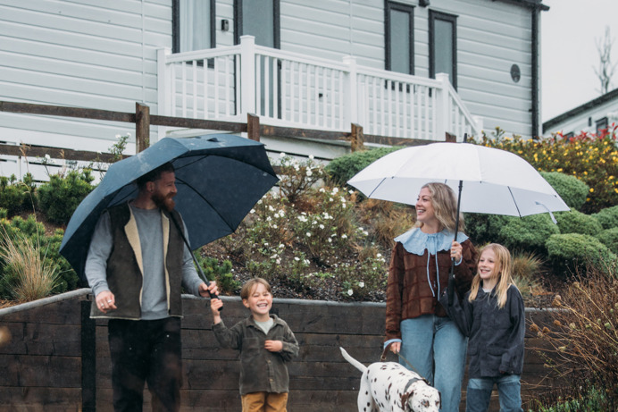 Family walking with dog on park in rain
