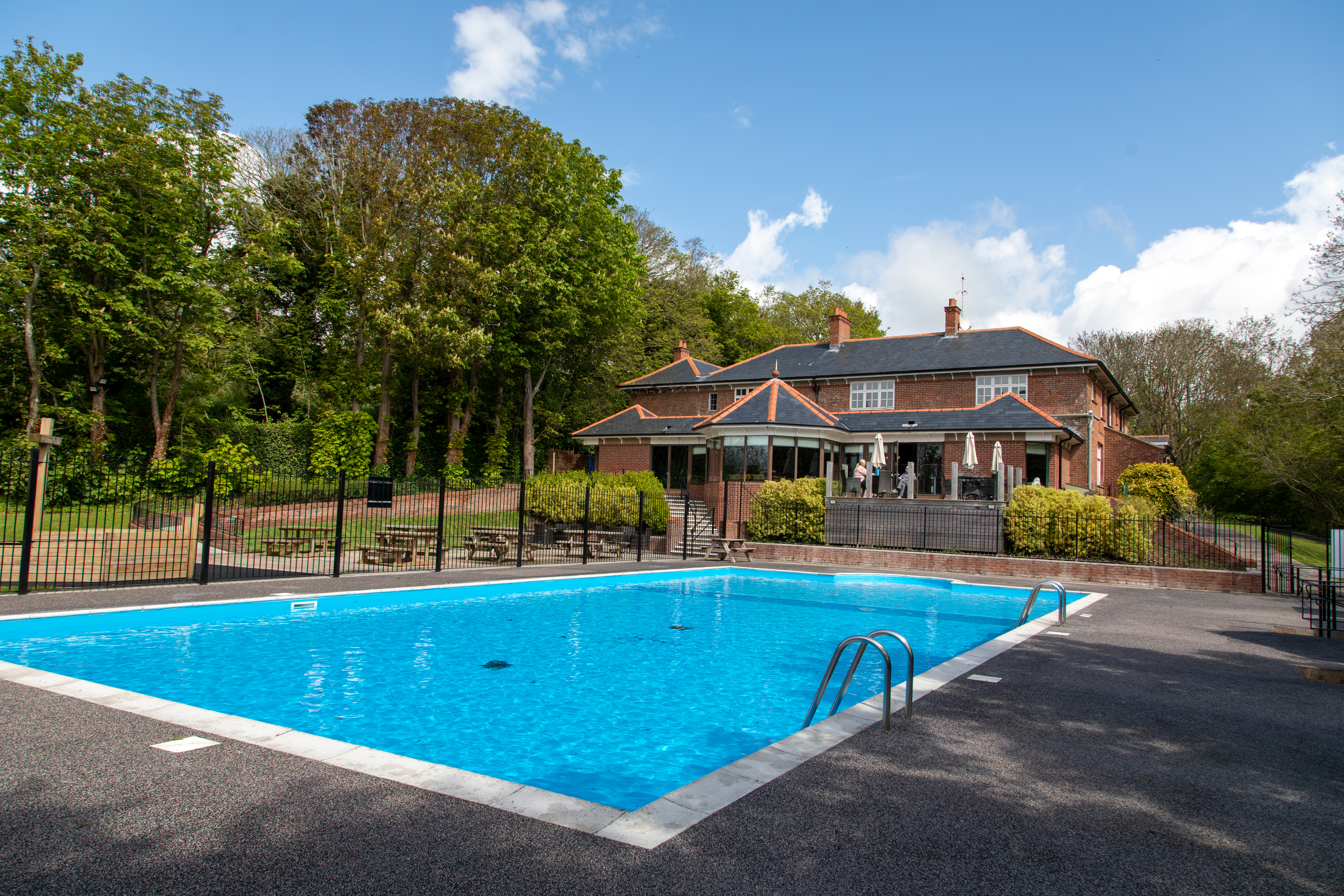 A country club with a large heated outdoor pool among countryside on a blue sunny day
