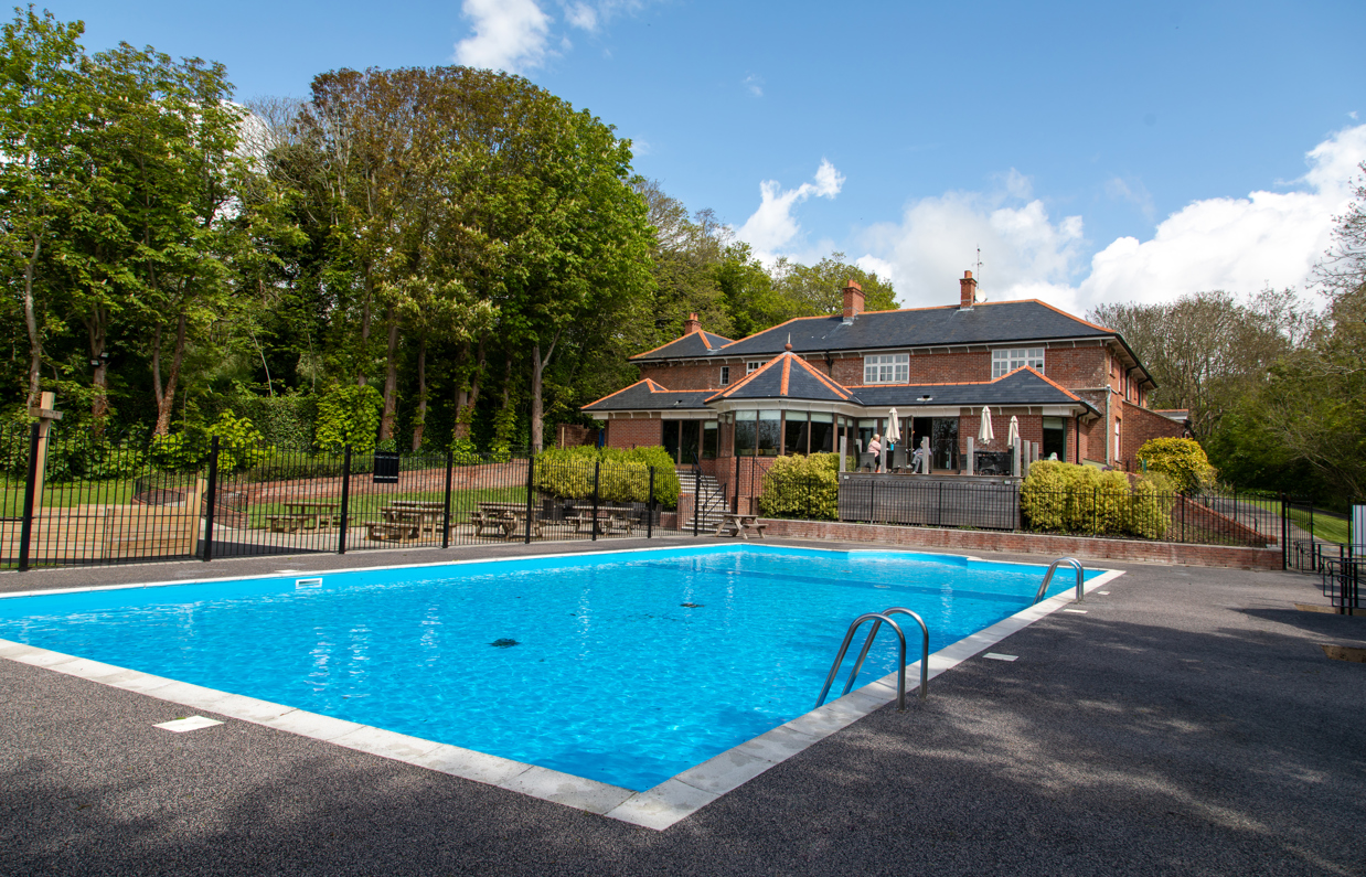 A country club with a large heated outdoor pool among countryside on a blue sunny day
