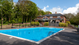 A country club with a large heated outdoor pool among countryside on a blue sunny day