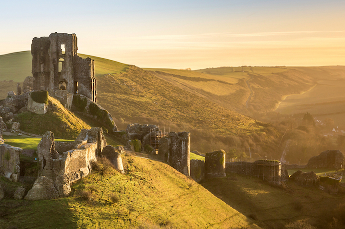 A castle ruins atop a hill with large grassy grounds