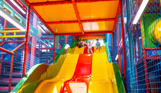 A group of young children going down a slide at a soft play