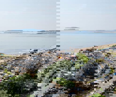 An aerial view of the coast of Weymouth Bay with a holiday park and theme park funfair