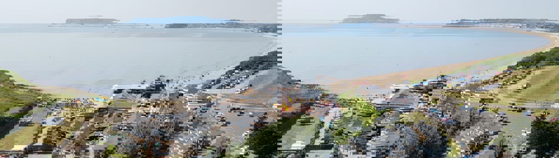 An aerial view of the coast of Weymouth Bay with a holiday park and theme park funfair