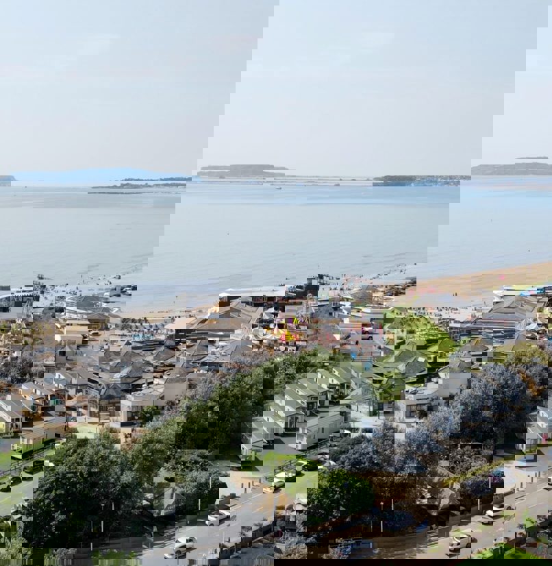 An aerial view of the coast of Weymouth Bay with a holiday park and theme park funfair