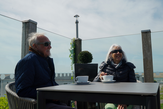 A couple sat at an outdoor table on a terrace with coffees