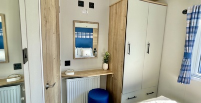 Internal of a caravan master bedroom with storage and dressing area