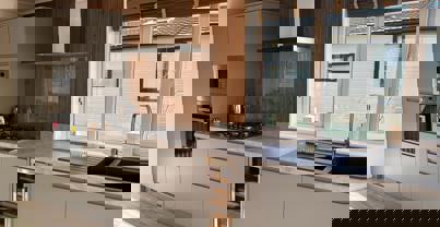 Fully fitted kitchen with grey units and dark wood panelling