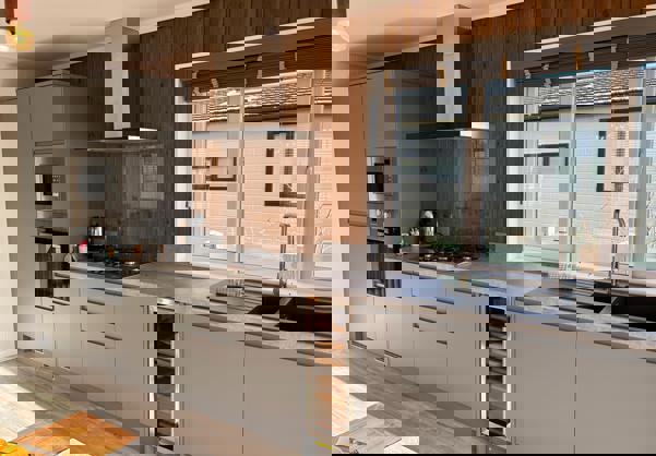 Fully fitted kitchen with grey units and dark wood panelling