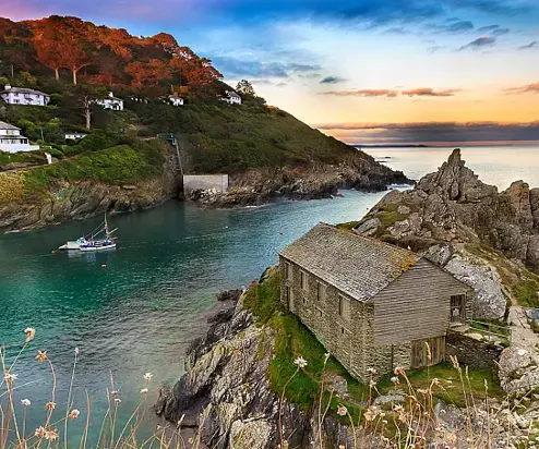 A small coastal town by the sea with blue waters and rolling hills in the background 