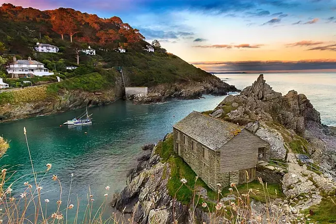 A small coastal town by the sea with blue waters and rolling hills in the background 