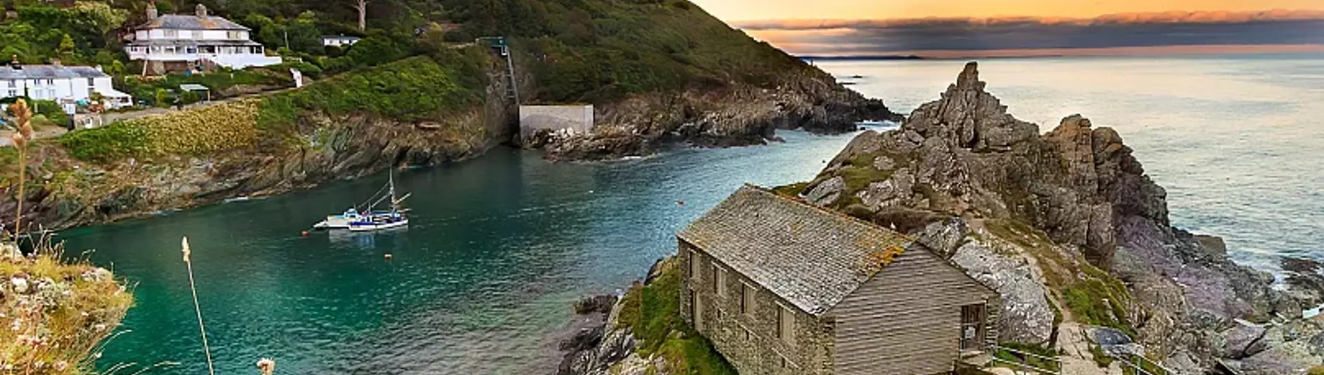 A small coastal town by the sea with blue waters and rolling hills in the background 