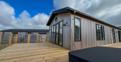 External of a luxury lodge on pitch with decking and hot tub