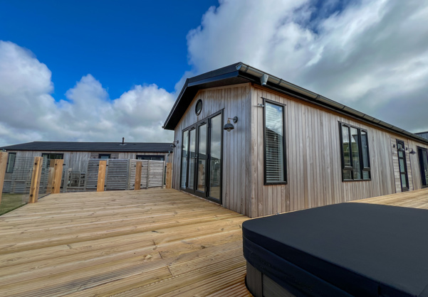 External of a luxury lodge on pitch with decking and hot tub