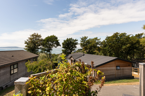 The view of the sea and Weymouth from the Kingfisher area of Osmington Mills Lodge Park surrounded by lodges and trees on a sunny, blue sky day