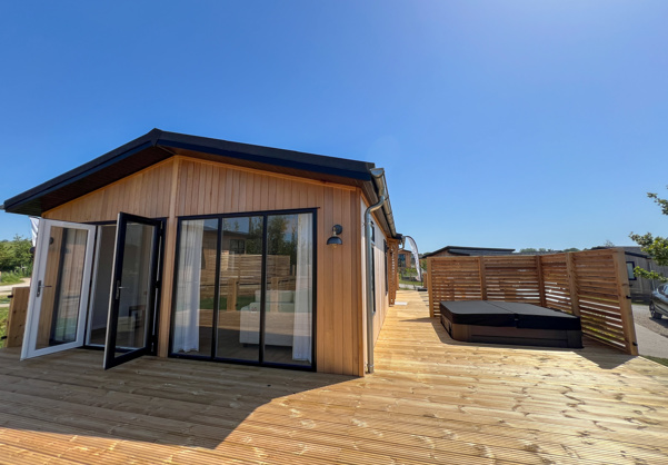 External of a luxury lodge on pitch with decking and hot tub