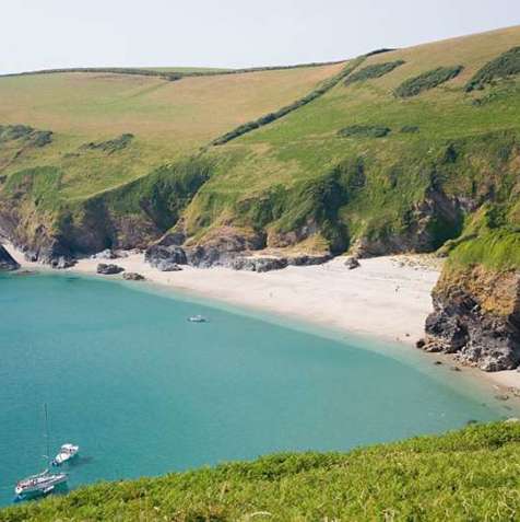 A small bay at the bottom of rolling countryside hills with blue water