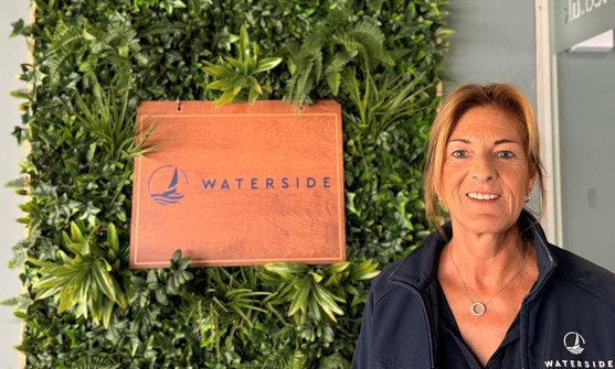 A smiling lady stood beside a Waterside sign