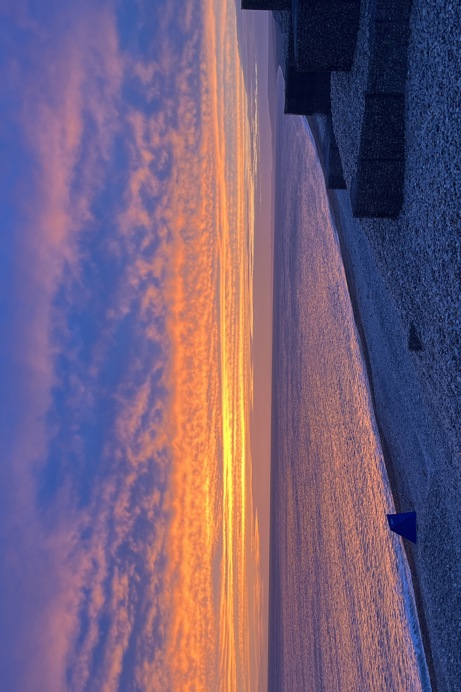 Chesil beach at sunset with colours of orange, yellow, pink & purple in the sky