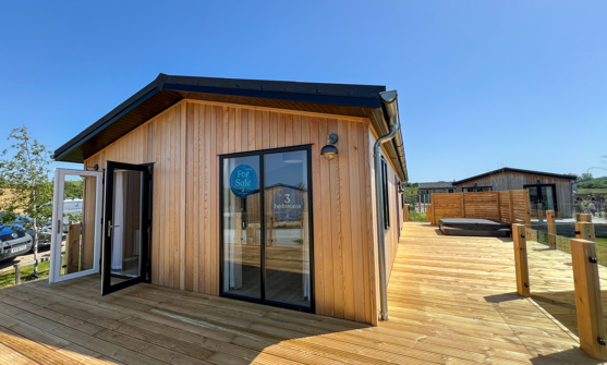 External of a luxury lodge on pitch with decking and hot tub