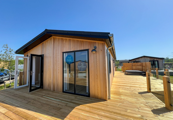 External of a luxury lodge on pitch with decking and hot tub
