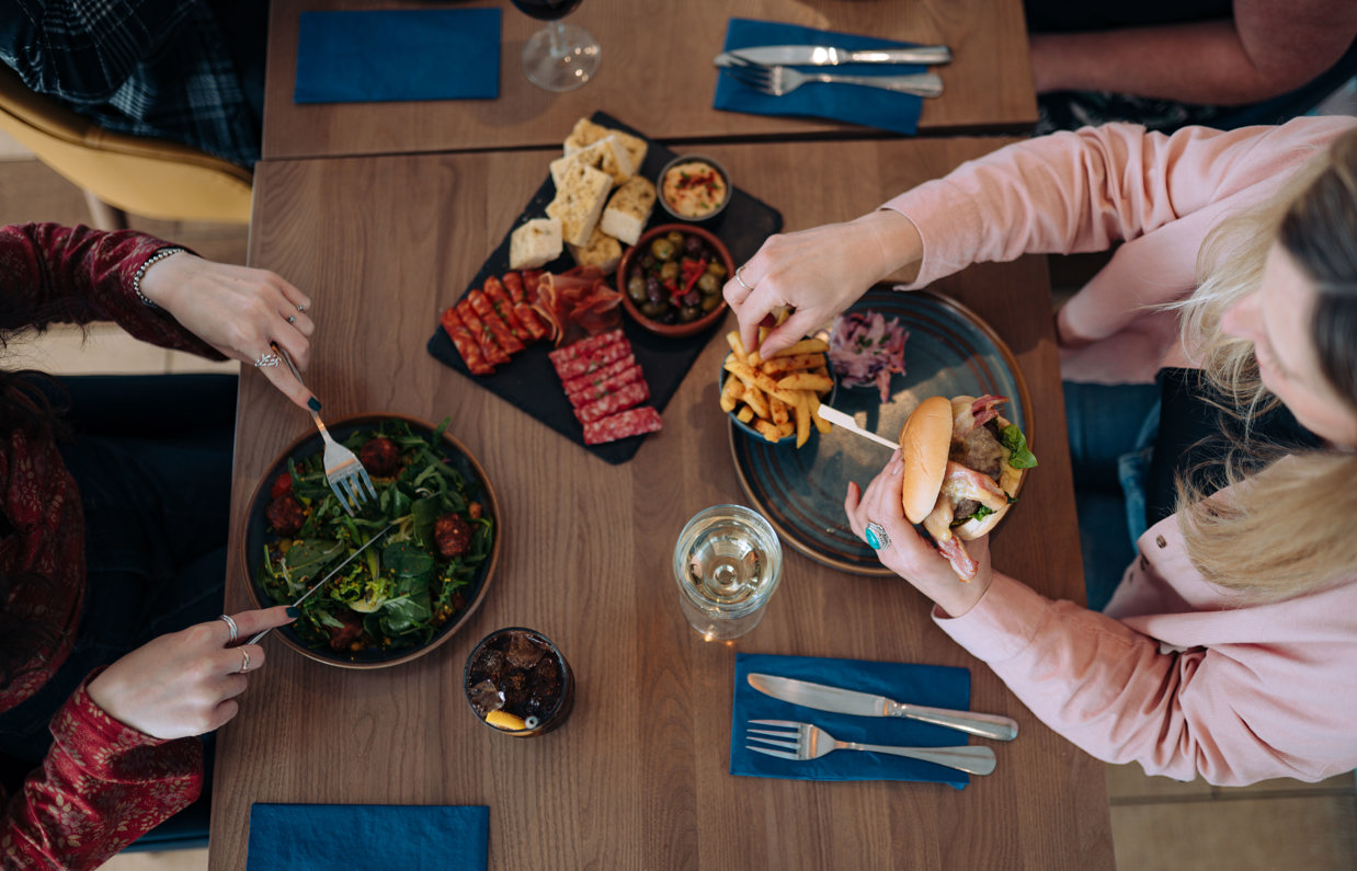 A charcuterie board, salad and burger on a table at Drift Bar & Grill taken from above