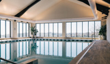 An indoor heated swimming pool within a barn style building with boho-chic styling and countryside views