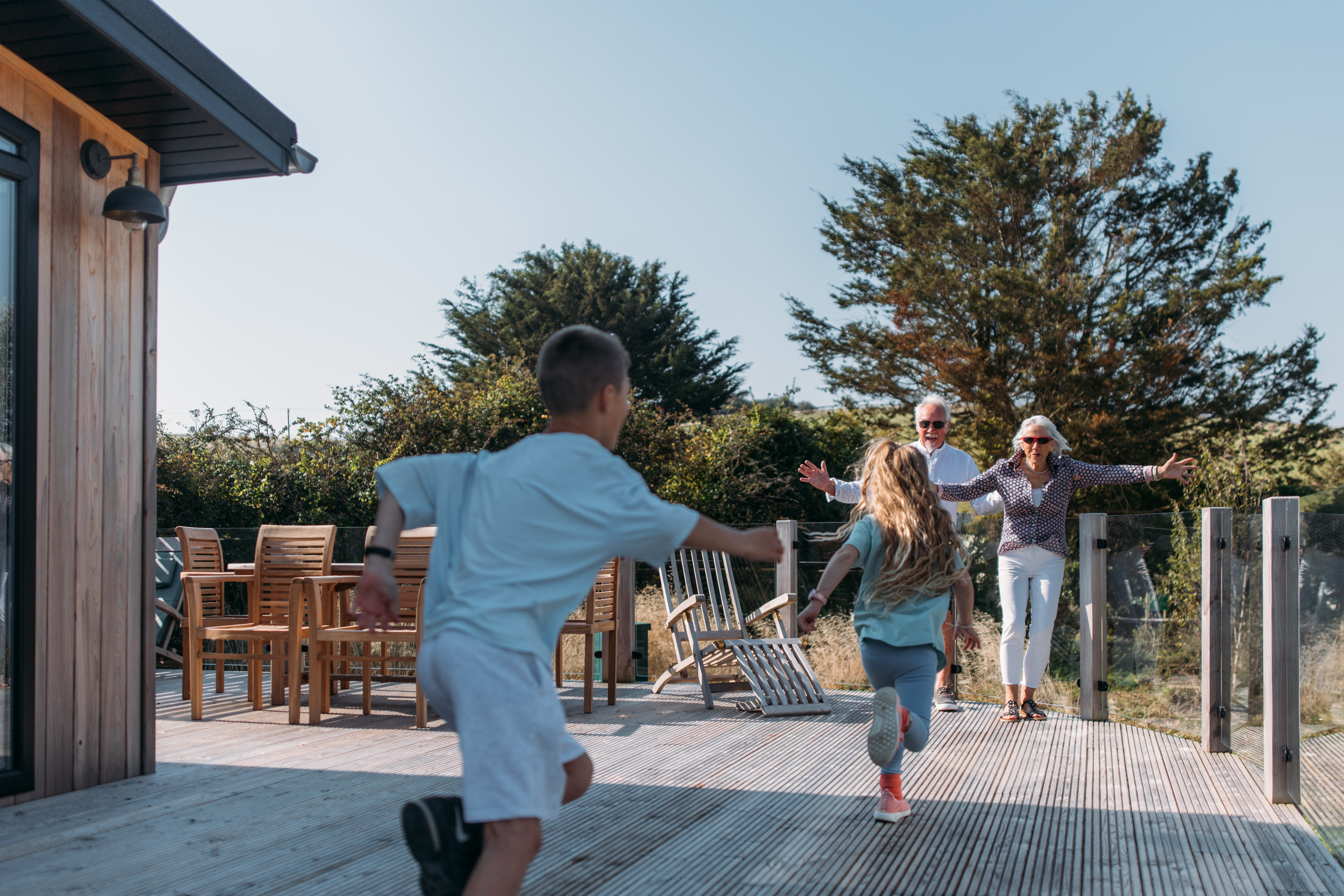 Grandparents welcoming grandchildren with open arms on deck