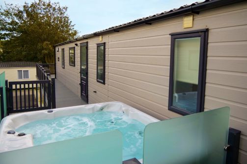 External of a caravan on pitch with decking and hot tub