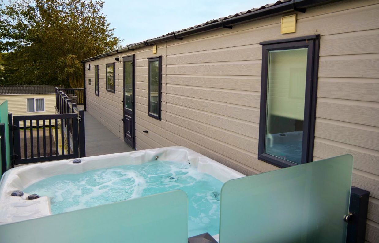 External of a caravan on pitch with decking and hot tub
