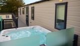 External of a caravan on pitch with decking and hot tub