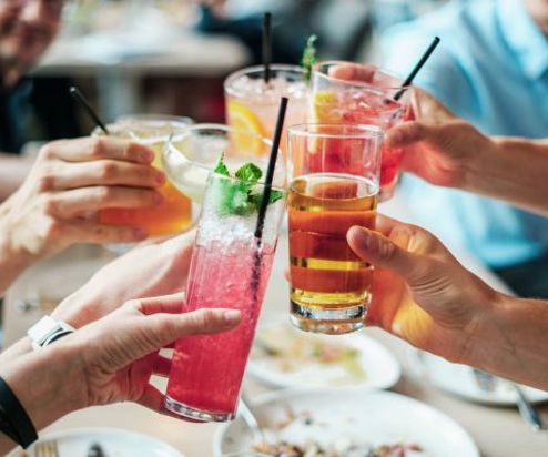 A group of people toasting a selection of different cocktails and drinks