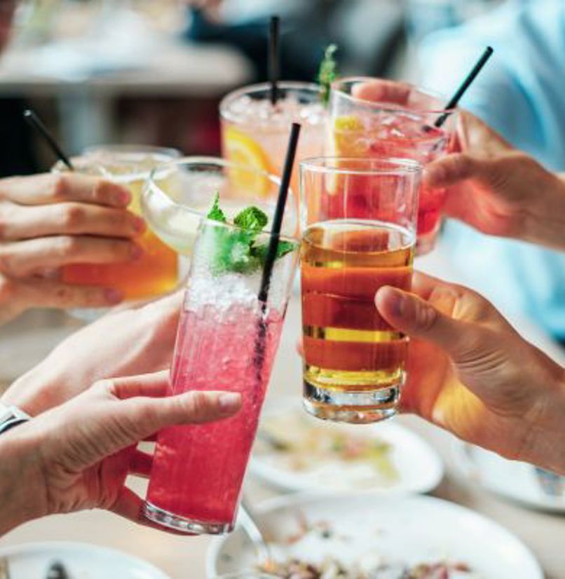 A group of people toasting a selection of different cocktails and drinks