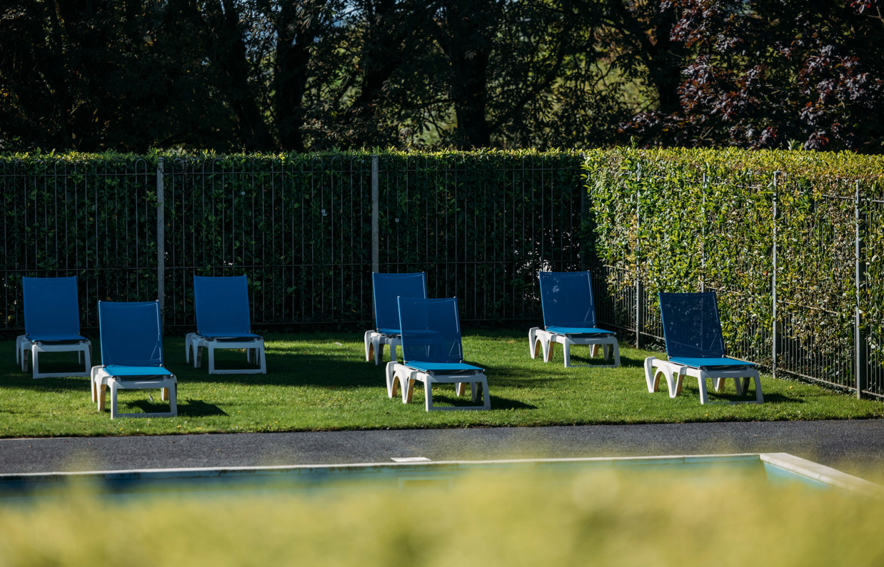 Sun loungers on a garden terrace beside a heated outdoor pool at Osmington Mills Lodge Park on a sunny day