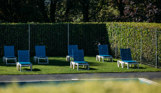 Sun loungers on a garden terrace beside a heated outdoor pool at Osmington Mills Lodge Park on a sunny day