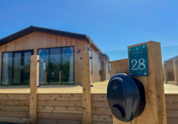 External of a luxury lodge on pitch with decking and EV charging point