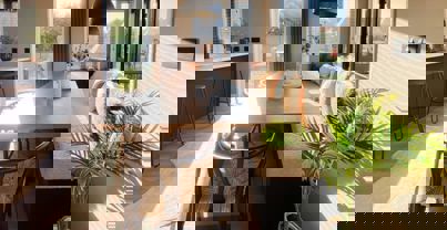 Large dining table with bench seating opposite open plan kitchen