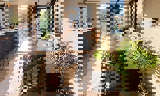 Large dining table with bench seating opposite open plan kitchen