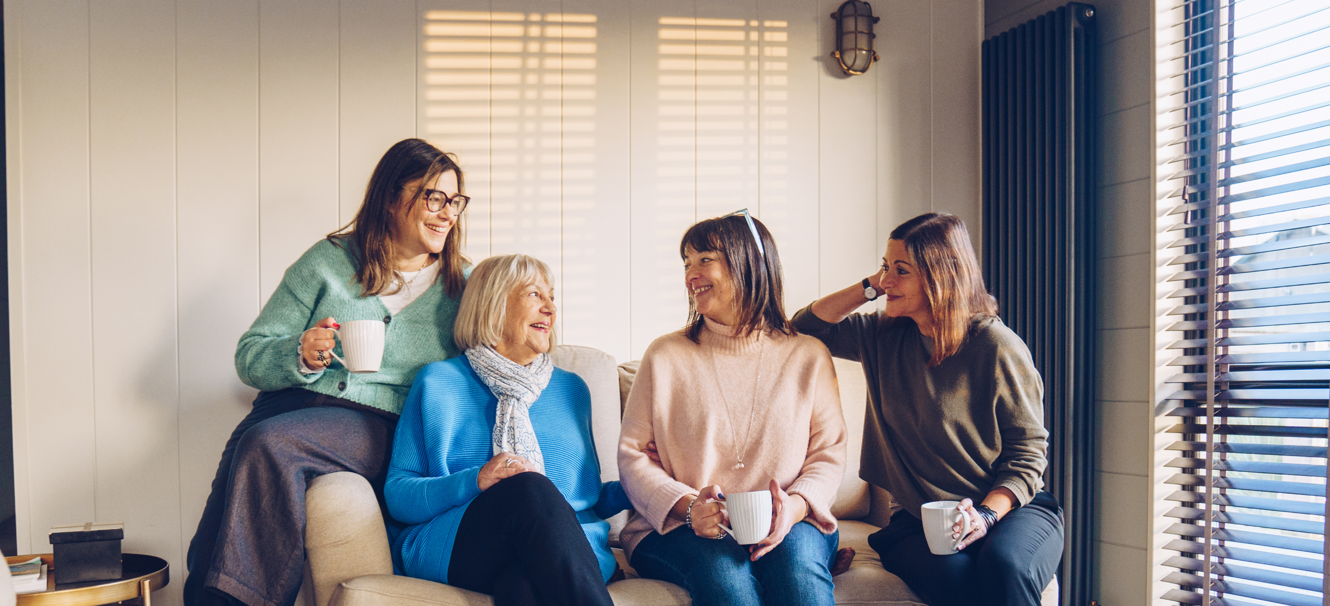 Family sat on sofa in lodge smiling at each other