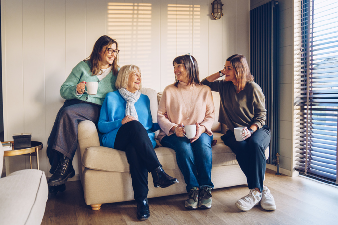 Family sat on sofa in lodge smiling at each other